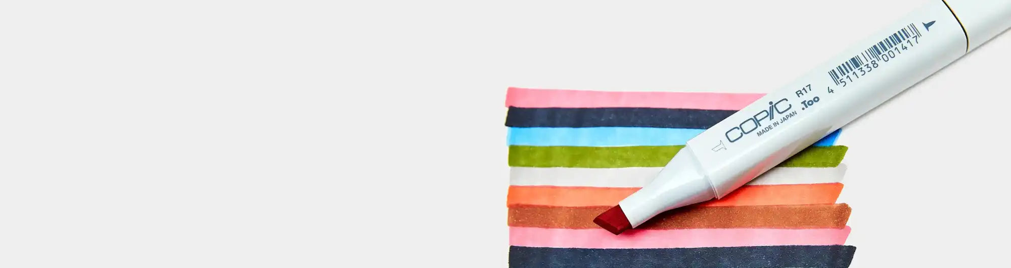A white art marker with a reddish-brown tip creating colorful swatches.