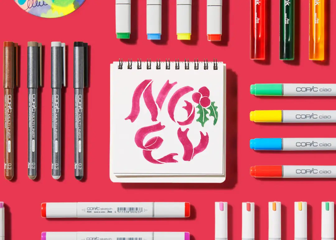 Copic ciao markers set with vibrant pink and green hues, featuring a floral design on the notebook cover.
